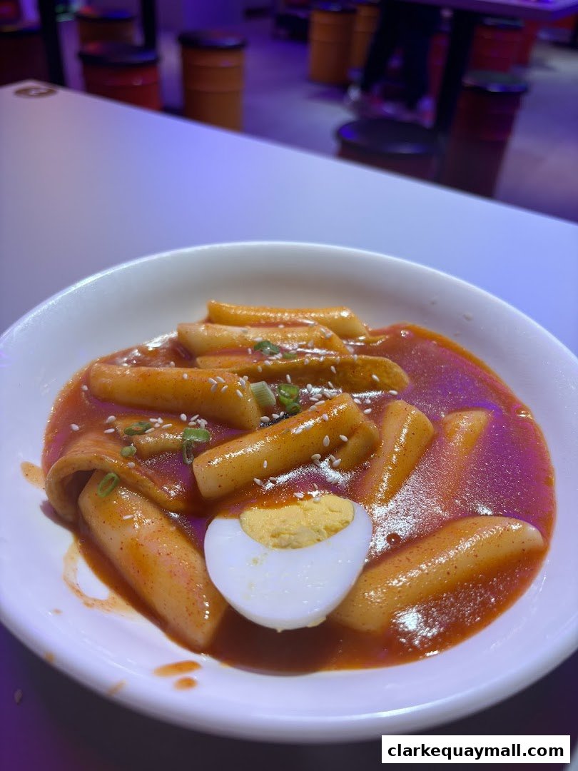 A close-up of Tteokbokki, a Korean street food, served in a white bowl with a boiled egg.