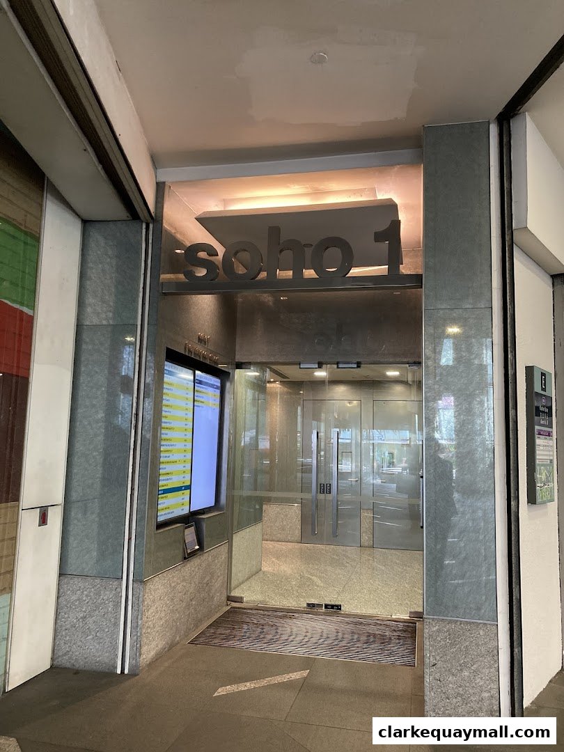 The entrance to Soho 1, a modern building with glass doors and signage.