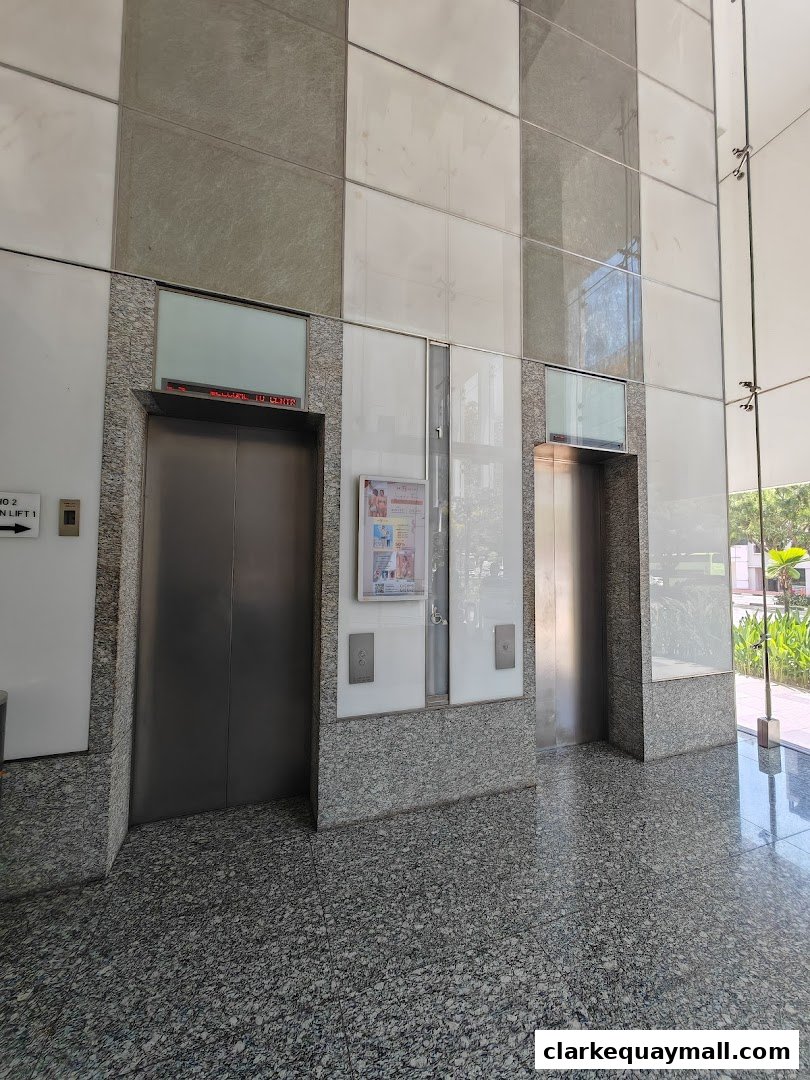 Two elevators in a modern building lobby with granite and marble finishes.