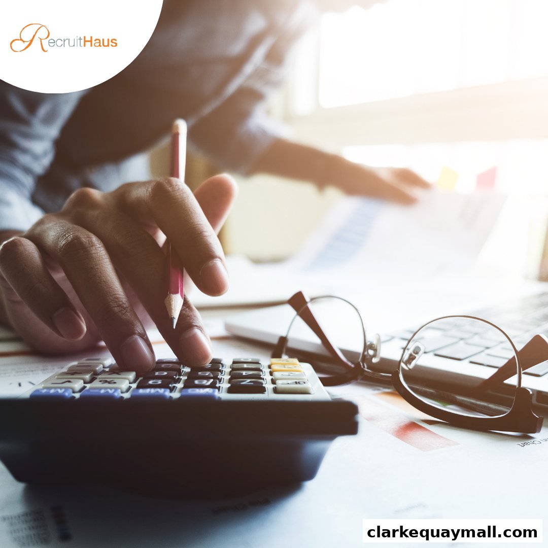 A person uses a calculator with a pencil, glasses, and papers on a desk.