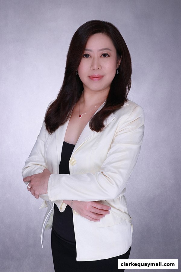 A professional portrait of a woman in a cream blazer and black top, with arms crossed.