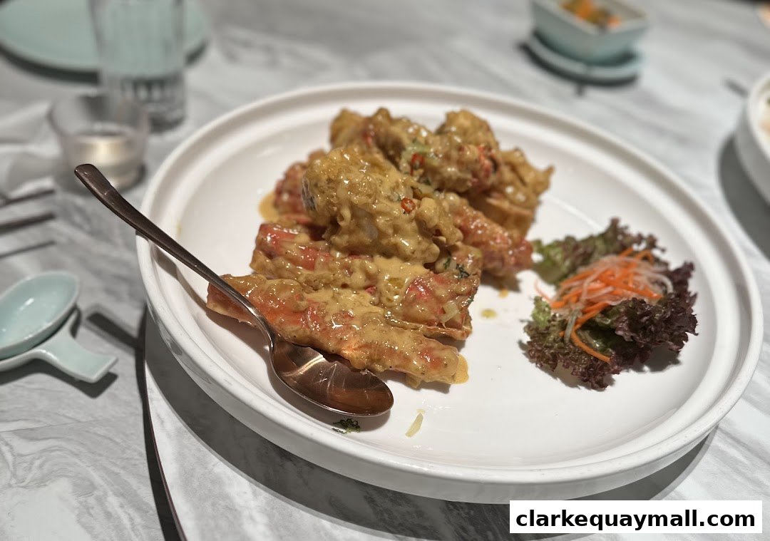 A plate of creamy seafood with a side salad and a spoon on a marble table.