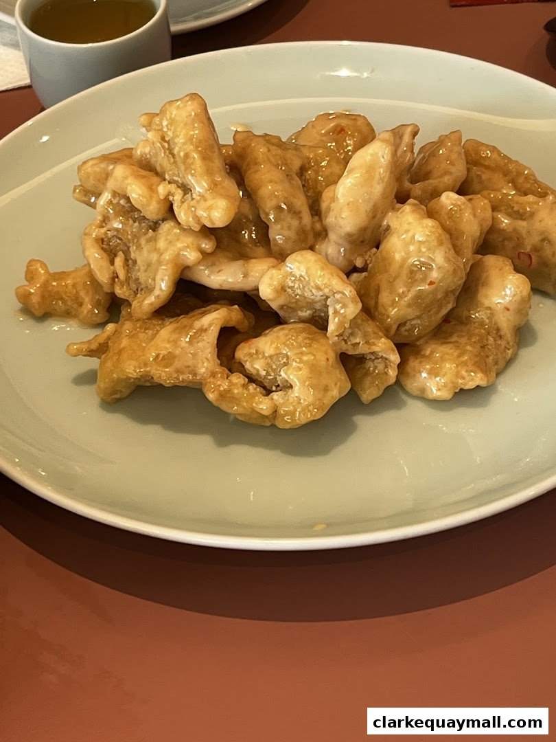 A plate of crispy, glazed chicken pieces served with a cup of tea.