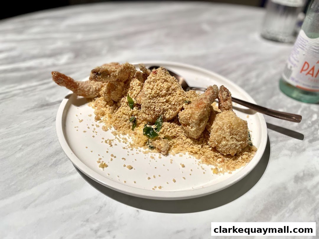 A plate of crispy fried prawns coated in breadcrumbs and served with a side of greens.