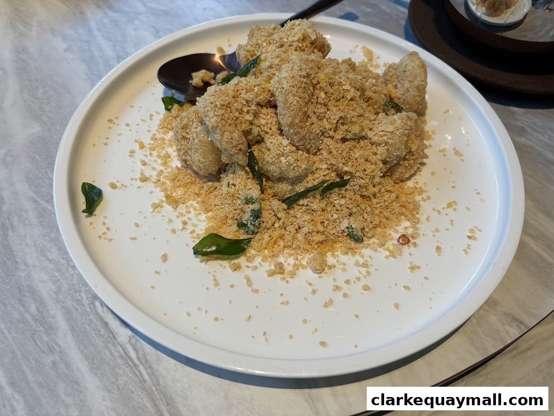 A plate of crispy fried seafood coated in breadcrumbs and herbs, served with a spoon.