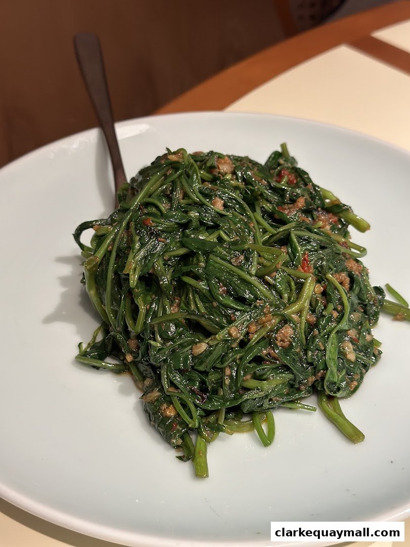 A plate of stir-fried water spinach with minced meat and chili.