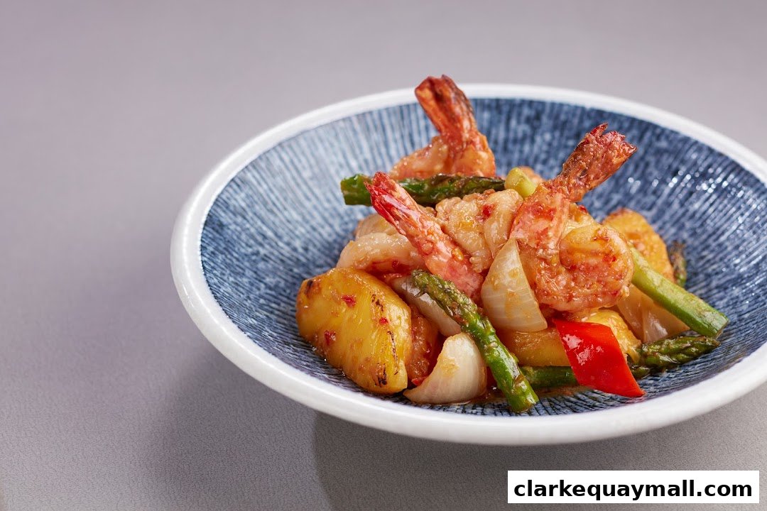 A close-up of a seafood dish with shrimp, pineapple, asparagus, and onions in a blue patterned bowl.
