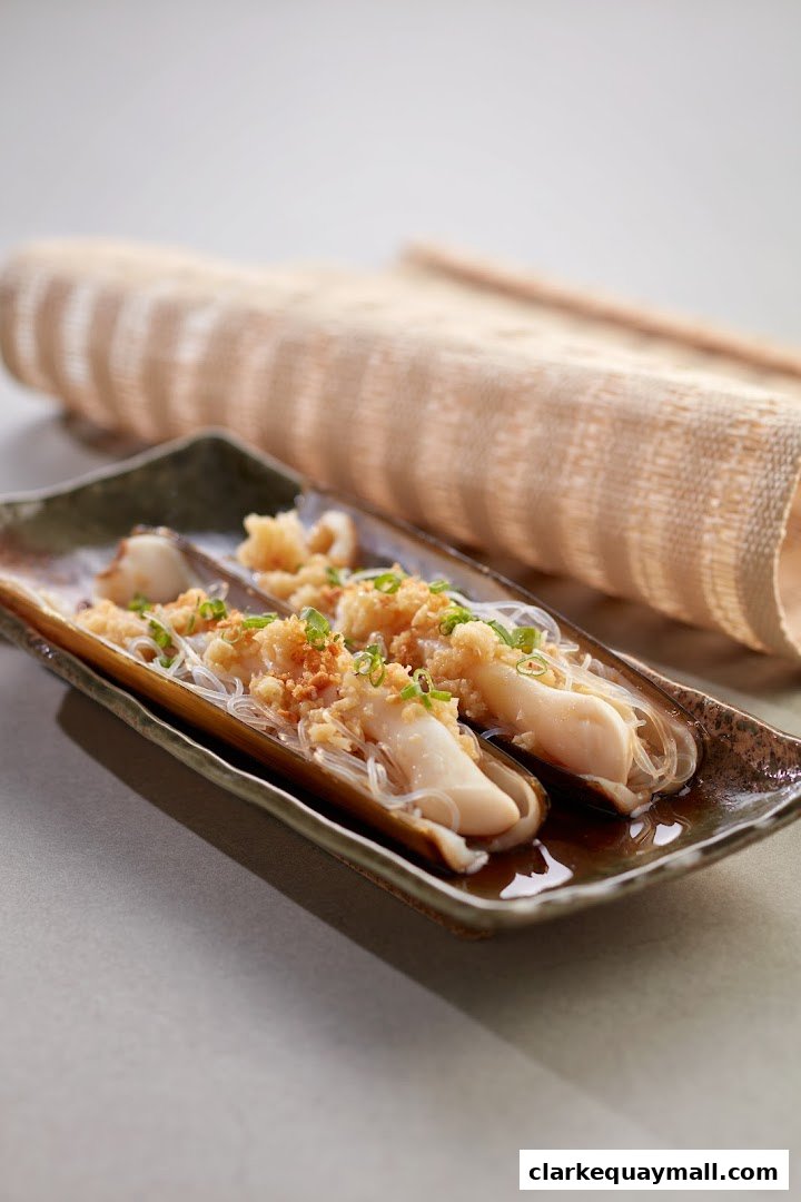 A close-up shot of steamed razor clams with garlic and vermicelli noodles.