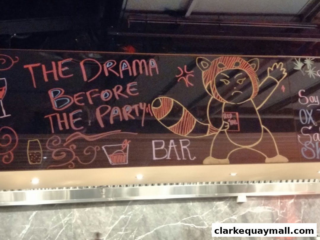 A chalkboard sign at RedTail Bar By Zouk features a cartoon red panda and text about pre-party drama.