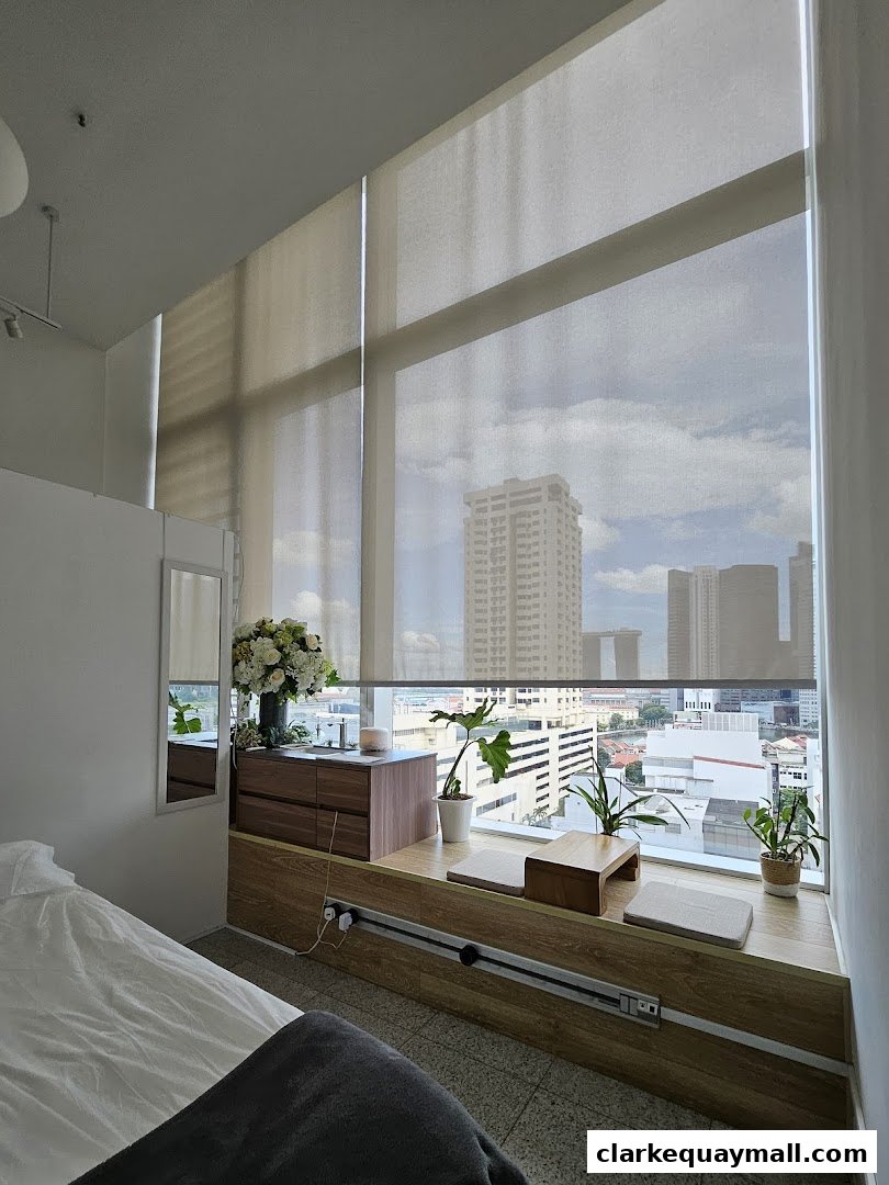 A serene room with a large window offering a city view, featuring plants and a comfortable seating area.