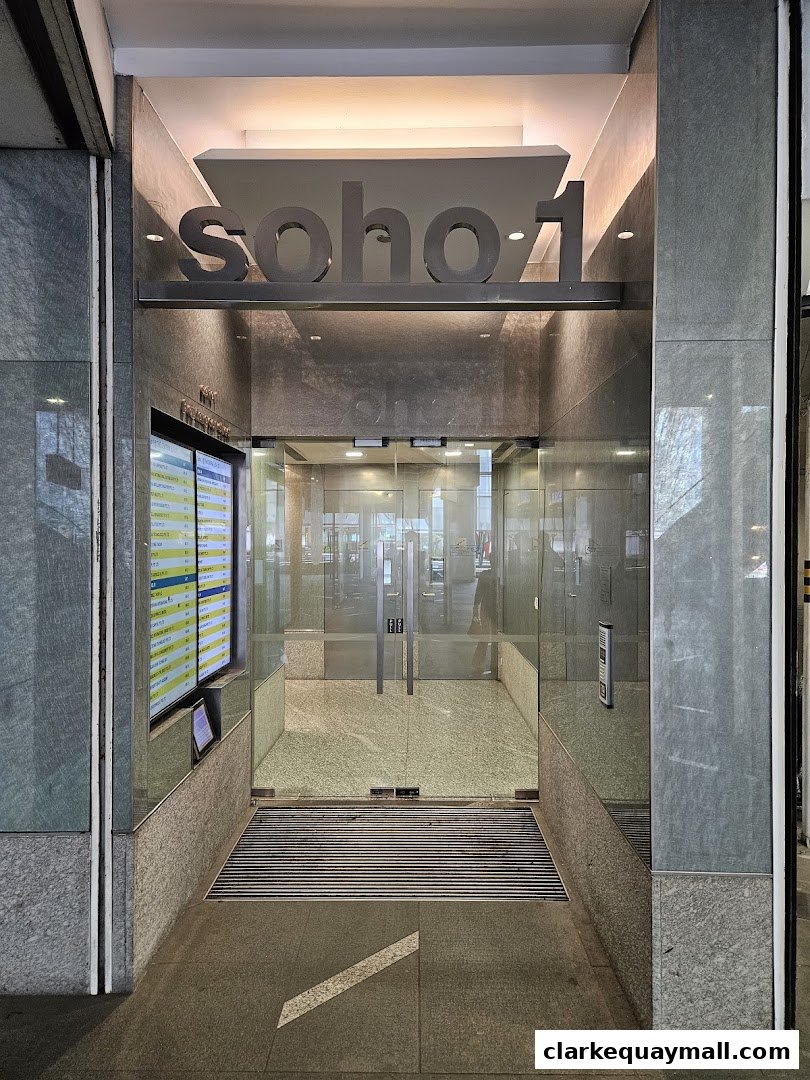 The entrance to Soho 1, featuring glass doors and signage.