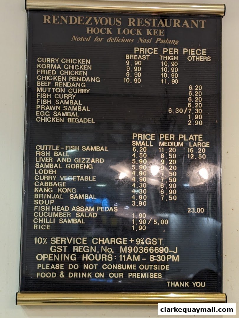 A black menu board with gold lettering listing various dishes and prices for Rendezvous Restaurant Hock Lock Kee.