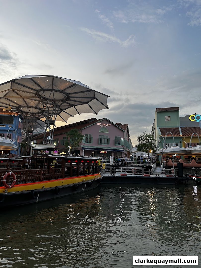 Boats docked by a river with buildings and people in the background.