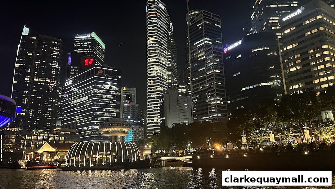Night view of a city skyline with illuminated skyscrapers and a waterfront promenade.