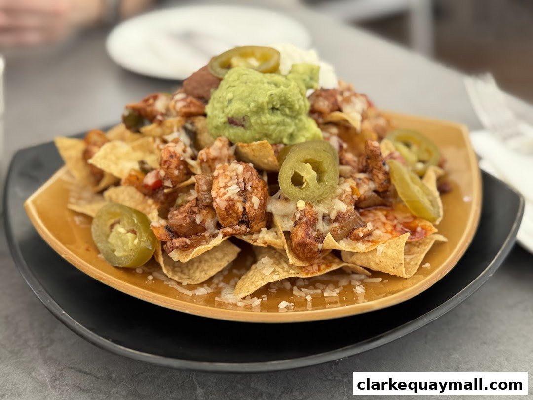 A plate of loaded nachos with chicken, guacamole, jalapenos, and cheese.