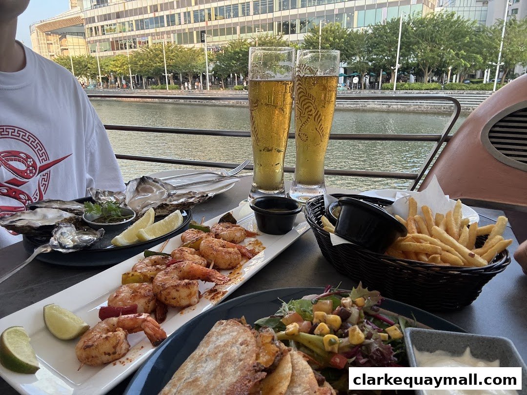 A table laden with seafood, fries, and beer with a waterfront view.
