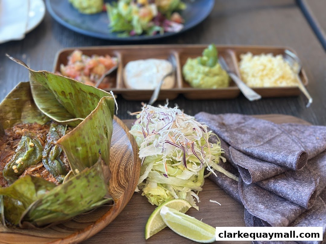 A close-up of a Mexican dish served with tortillas, guacamole, salsa, and shredded cheese.