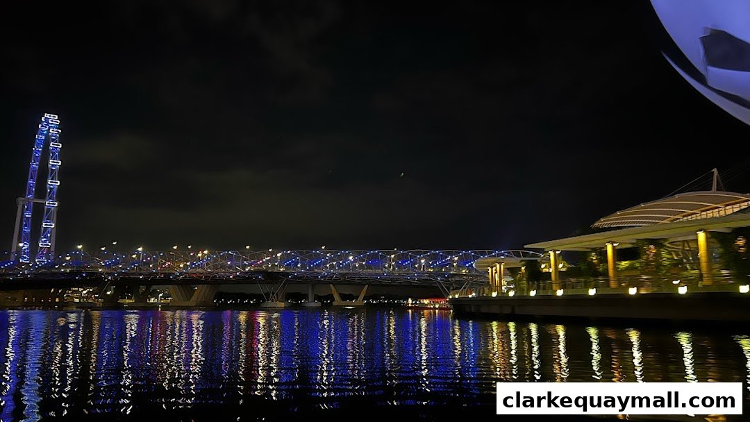 Night view of a waterfront with a bridge, Ferris wheel, and illuminated buildings.
