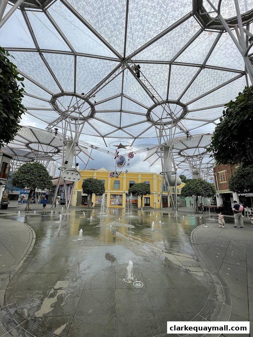 A wide shot of a plaza with fountains and a distinctive modern canopy structure.