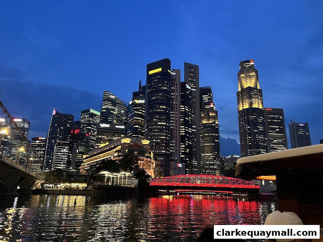 Night view of Singapore skyline with illuminated skyscrapers and a red bridge over the river.