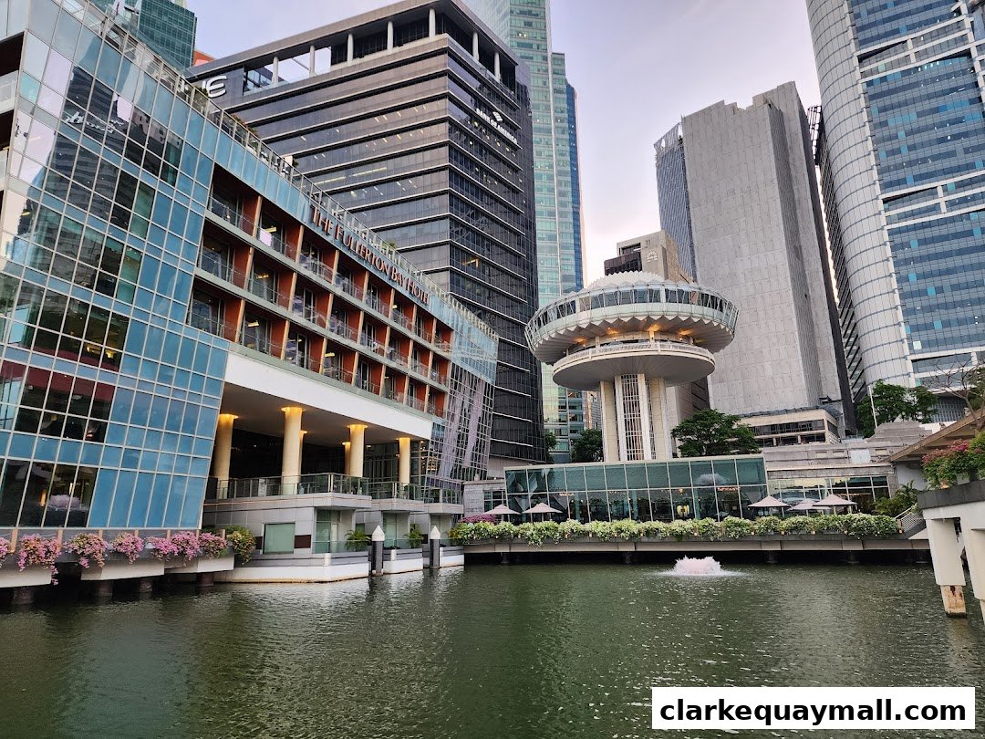 A waterfront view of modern buildings and a hotel with a fountain in the water.