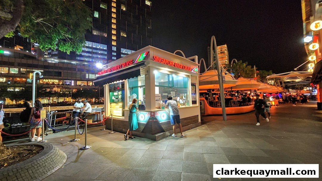 A Singapore River Cruise kiosk at night with people queuing.