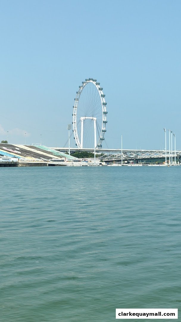 A large Ferris wheel stands tall against a clear blue sky, overlooking a body of water.
