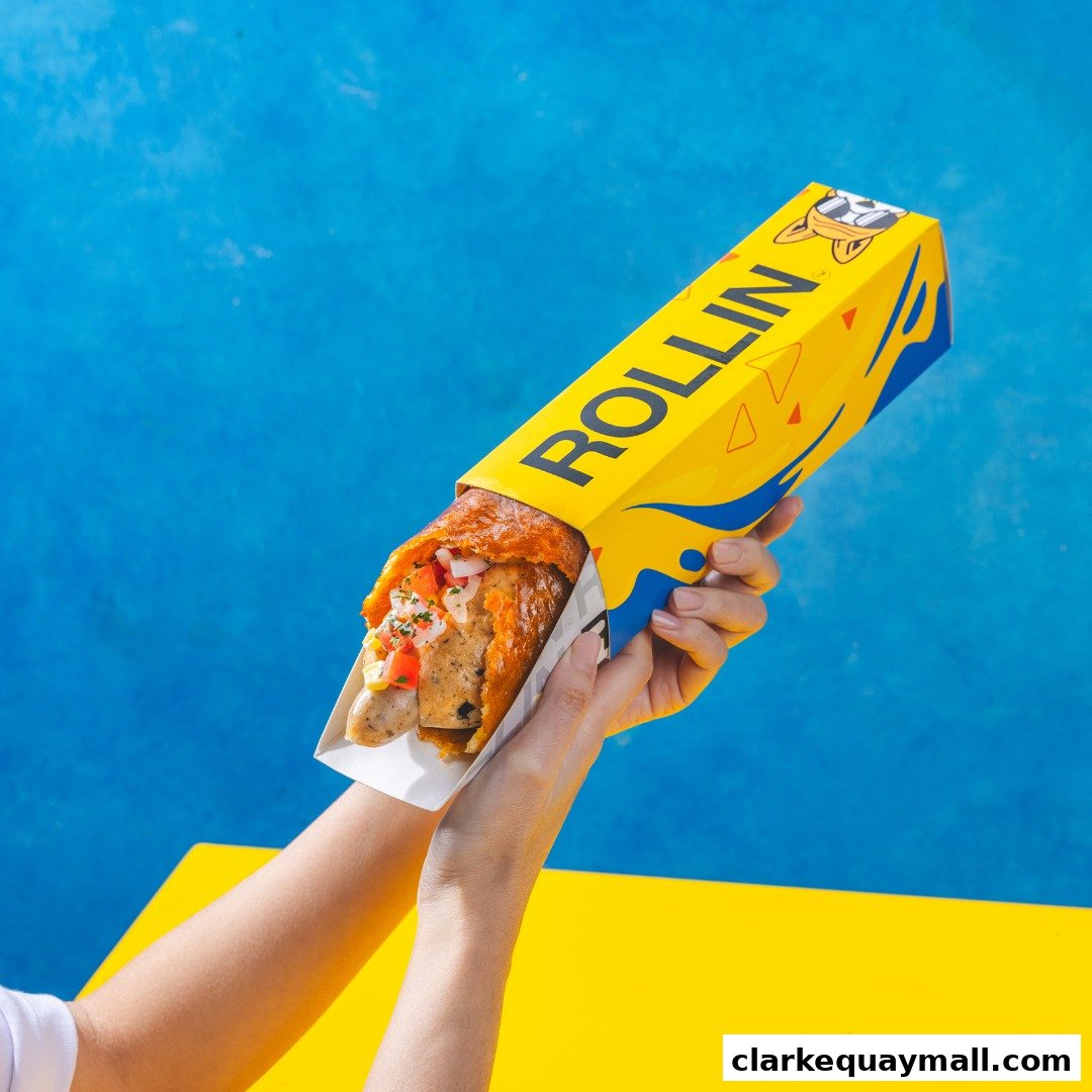 Hands holding a delicious cheese dog wrapped in bright yellow packaging.