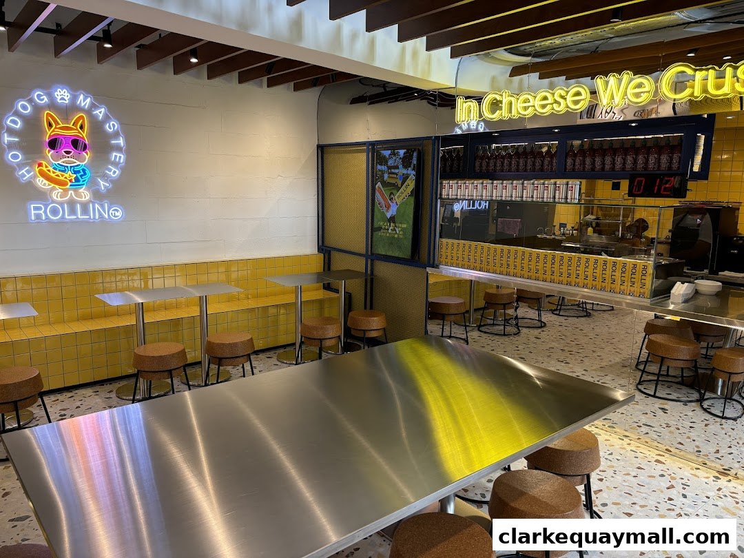 Interior of a modern cheese dog shop with neon signs and yellow tiled seating.