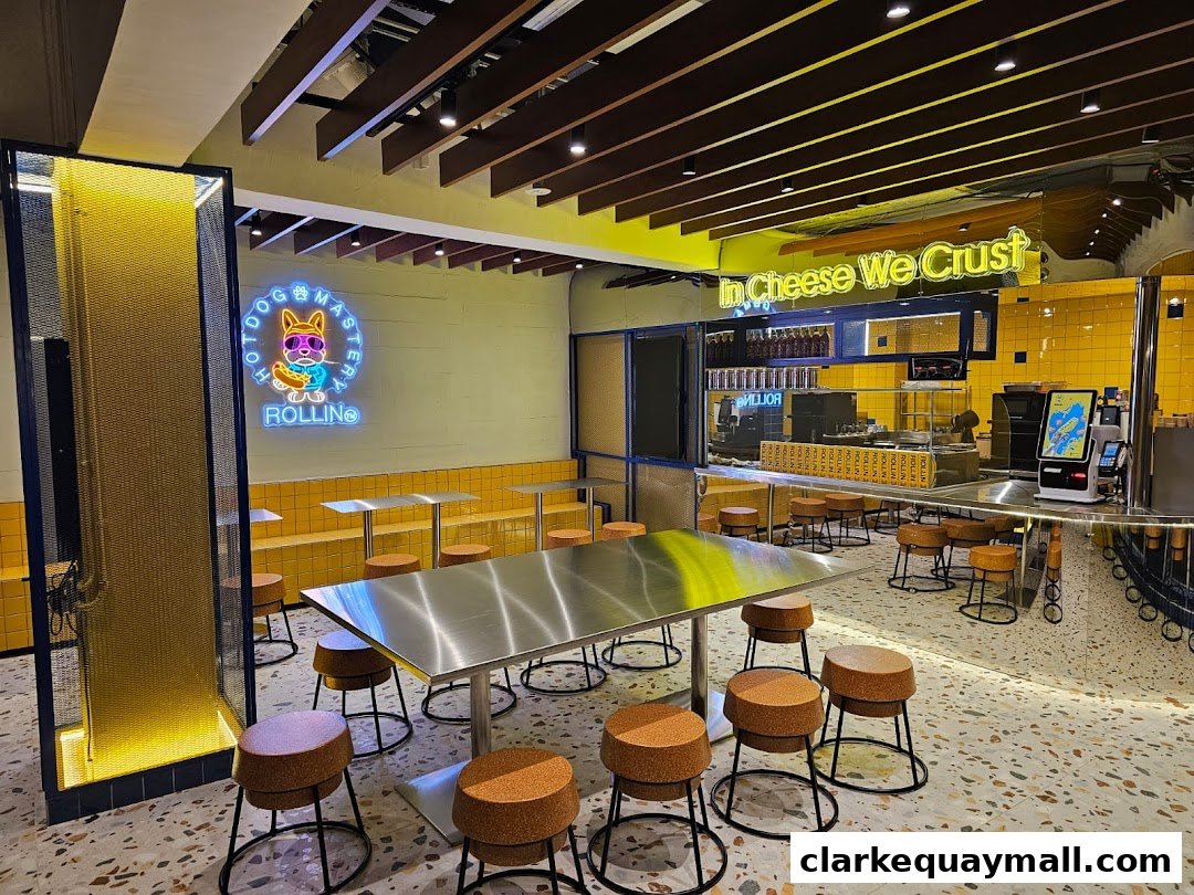 Interior of a modern cheese dog shop with neon signs and yellow accents.