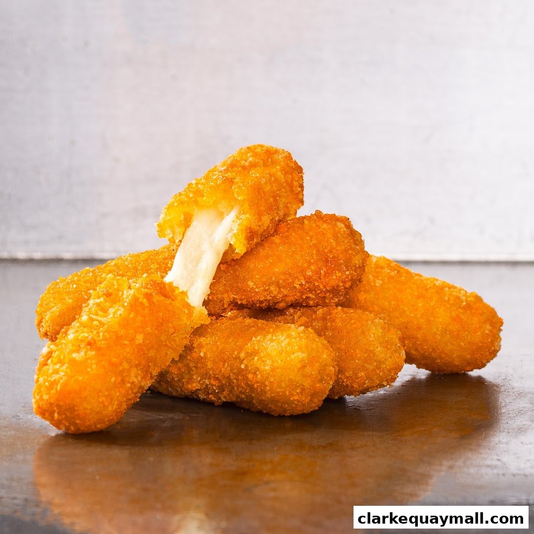 A pile of golden-brown, crispy cheese sticks with melted cheese oozing from one.