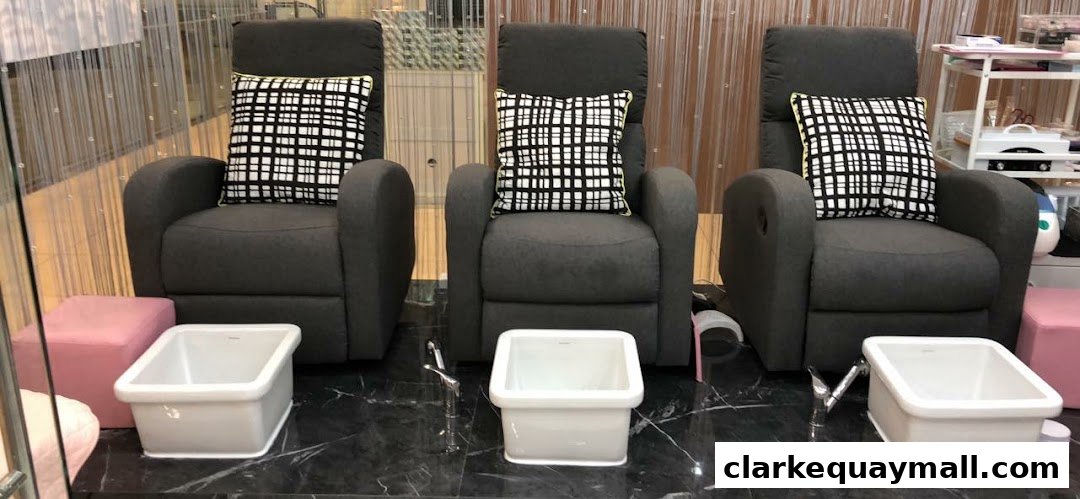Three comfortable pedicure chairs with foot baths and decorative pillows.