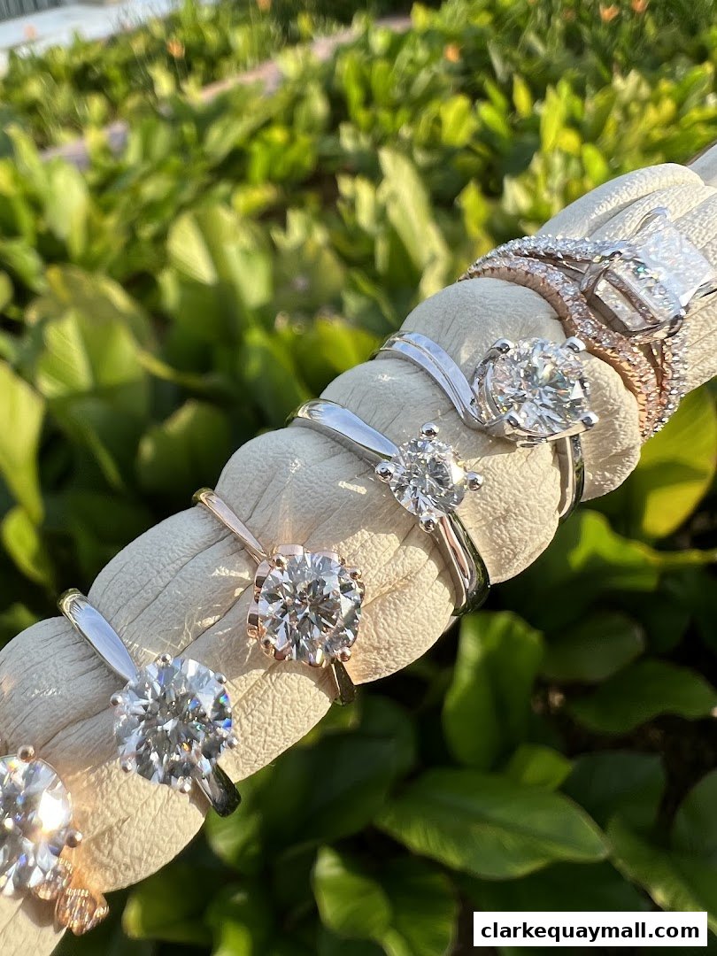 A collection of sparkling diamond rings displayed on a white surface with a green leafy background.