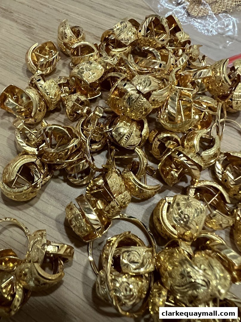 A pile of intricately designed gold hoop earrings with detailed carvings.