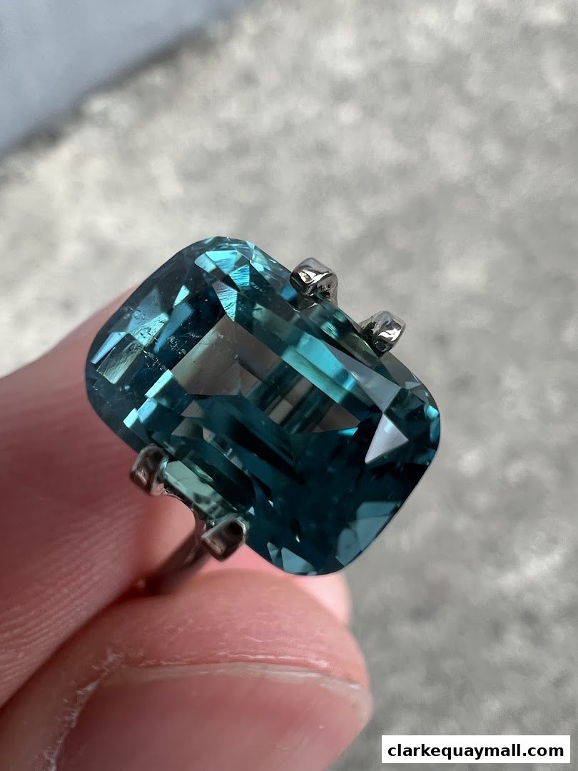 A close-up shot of a large, emerald-cut blue gemstone set in a silver ring.