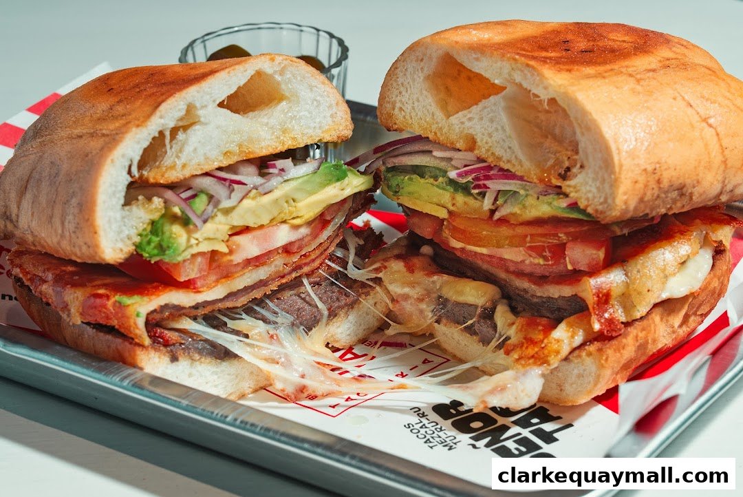 A delicious, fully loaded sandwich with avocado, tomato, onions, and melted cheese.