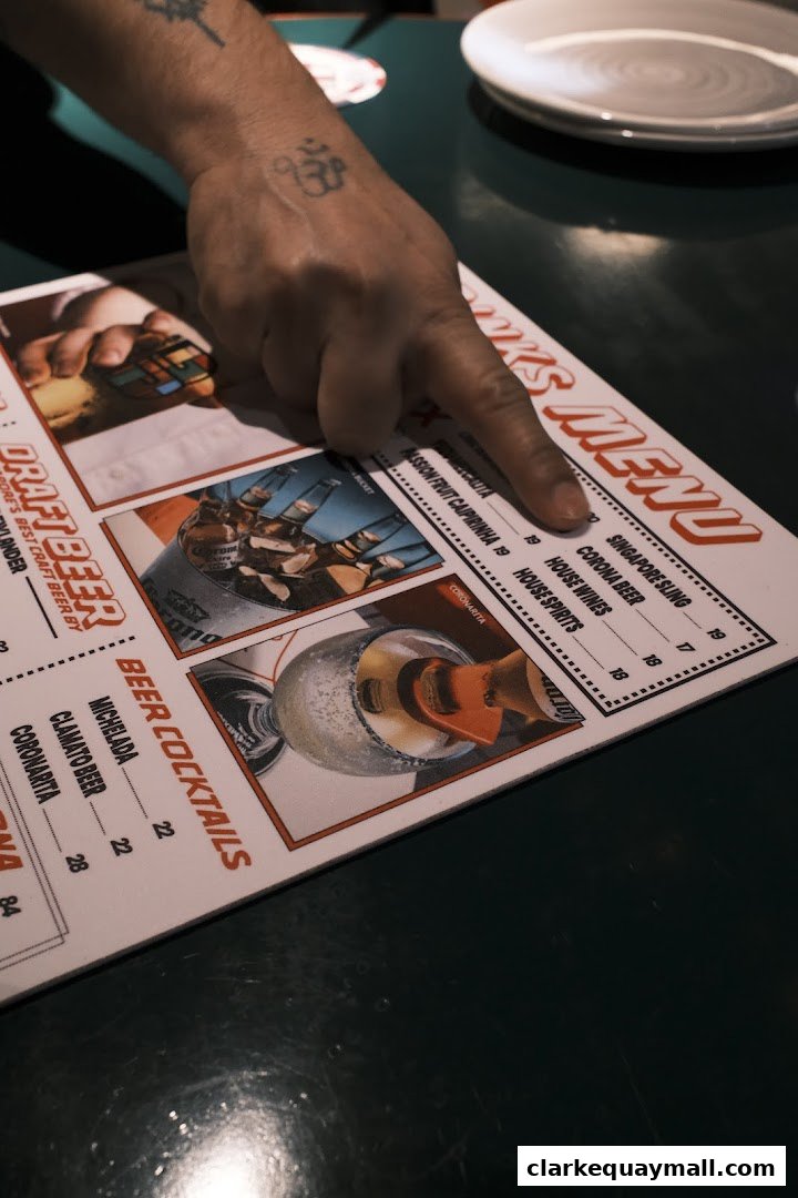 A hand points to a menu featuring drinks like beer cocktails and house spirits.