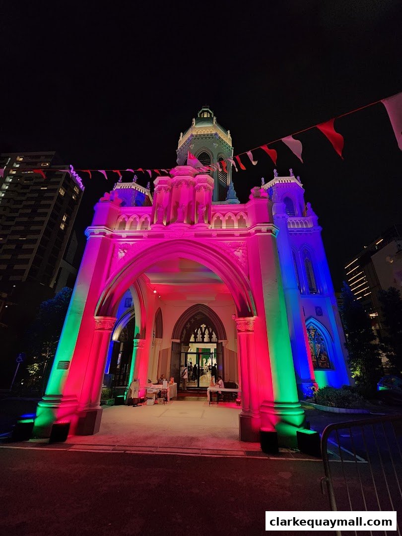 A building with gothic architecture is illuminated by colorful lights at night.