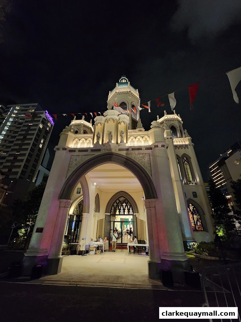 A grand church building at night, illuminated with festive lights and flags.