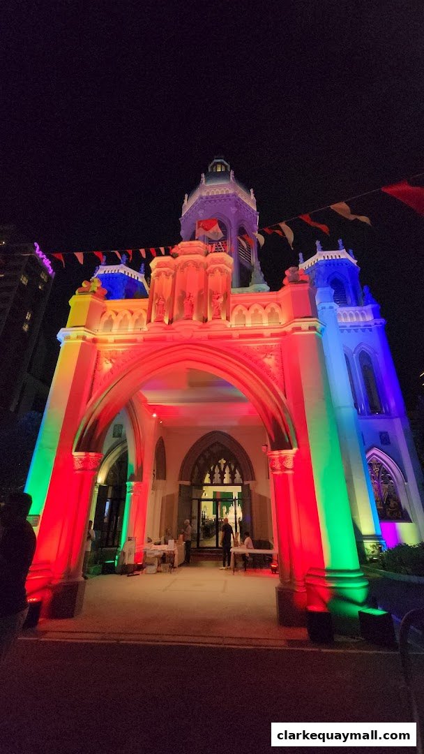 A building facade illuminated with colorful lights, featuring an arched entrance and people milling about.