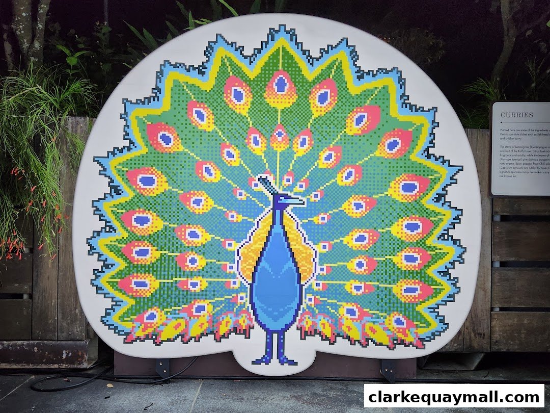 A large pixel art peacock display with a sign for curries in the background.
