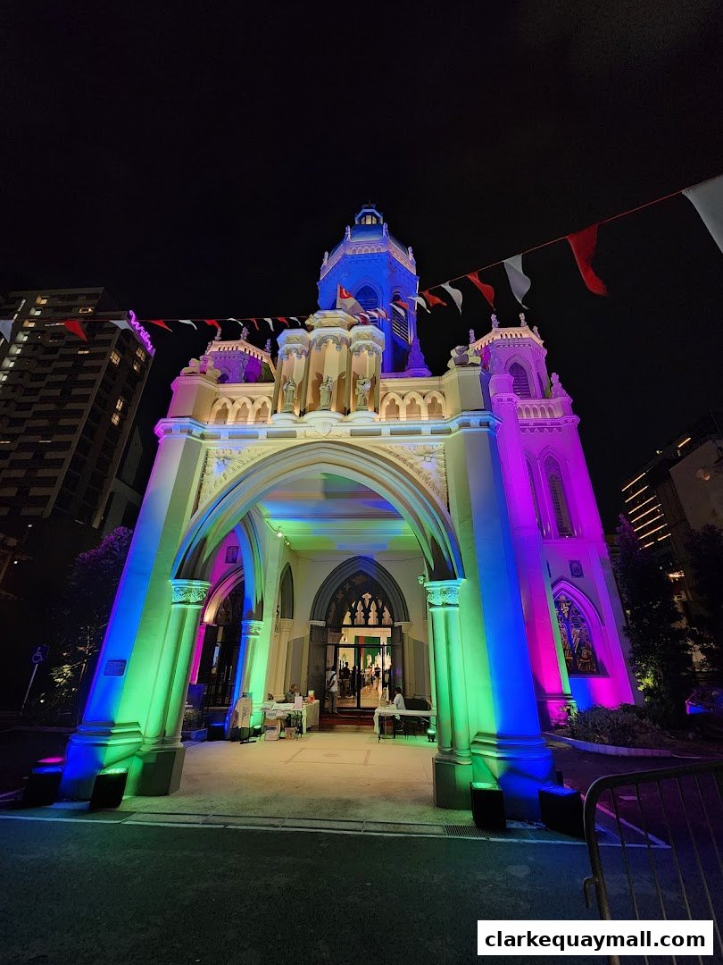A grand building entrance illuminated with colorful lights and festive flags at night.
