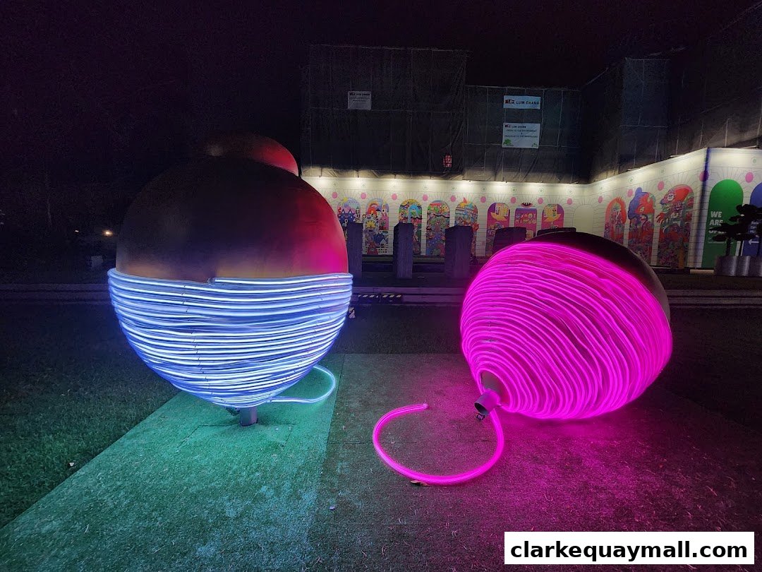Two large, spherical art installations illuminated with neon lights at night.