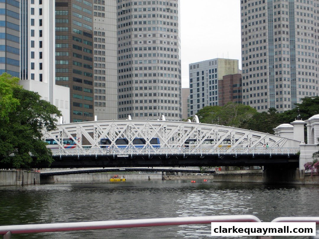 A white bridge spans a river with modern buildings in the background.
