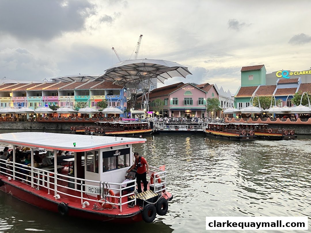 Boats docked along a river with colorful buildings and a cloudy sky.