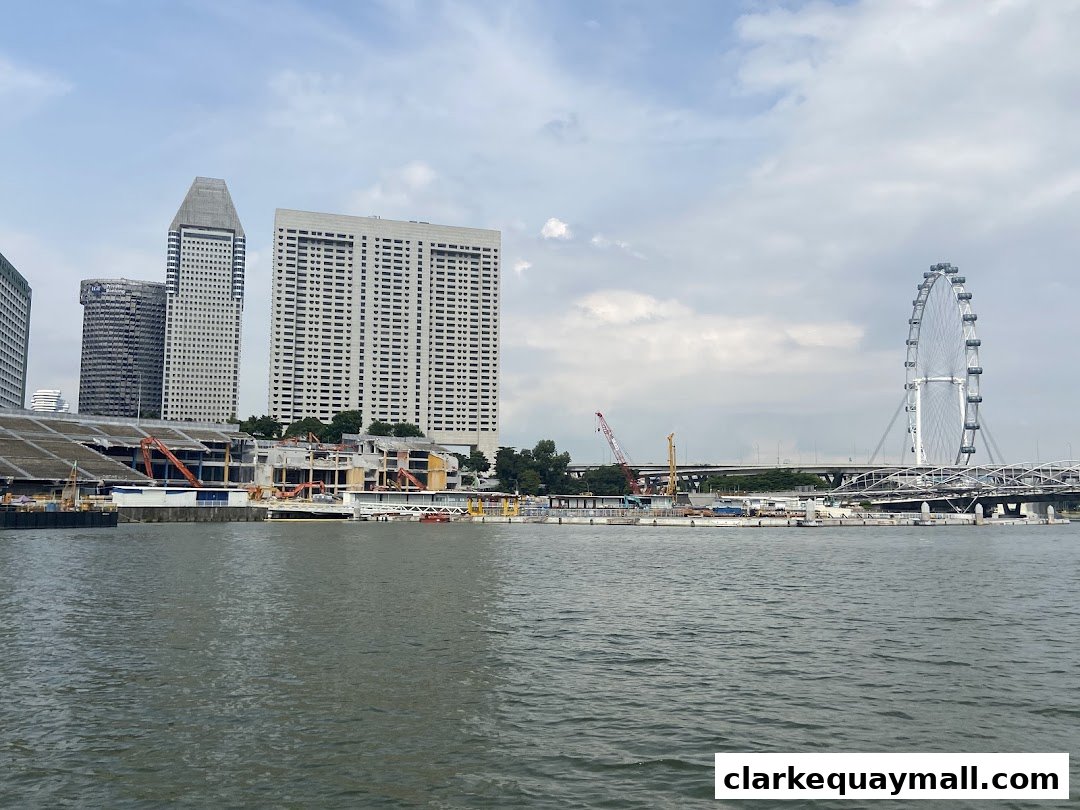 A scenic view of the Singapore River with city skyline and a Ferris wheel.