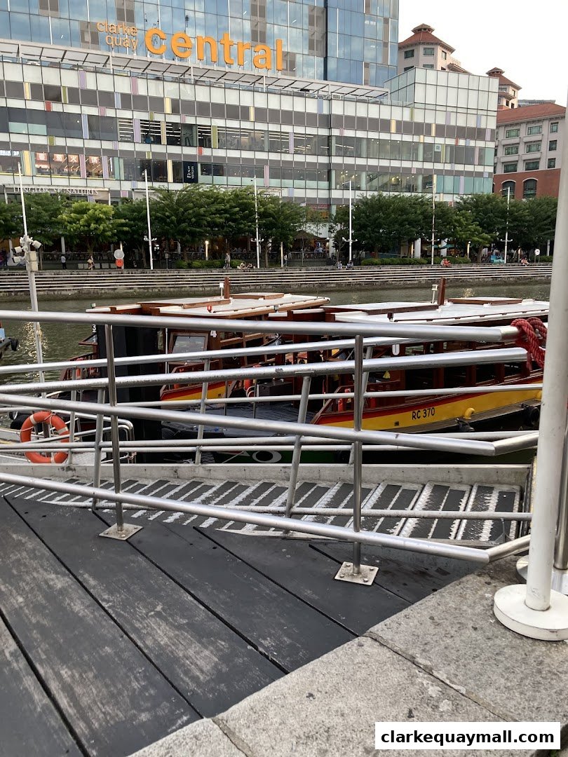 Boats docked by a river with a modern building in the background.