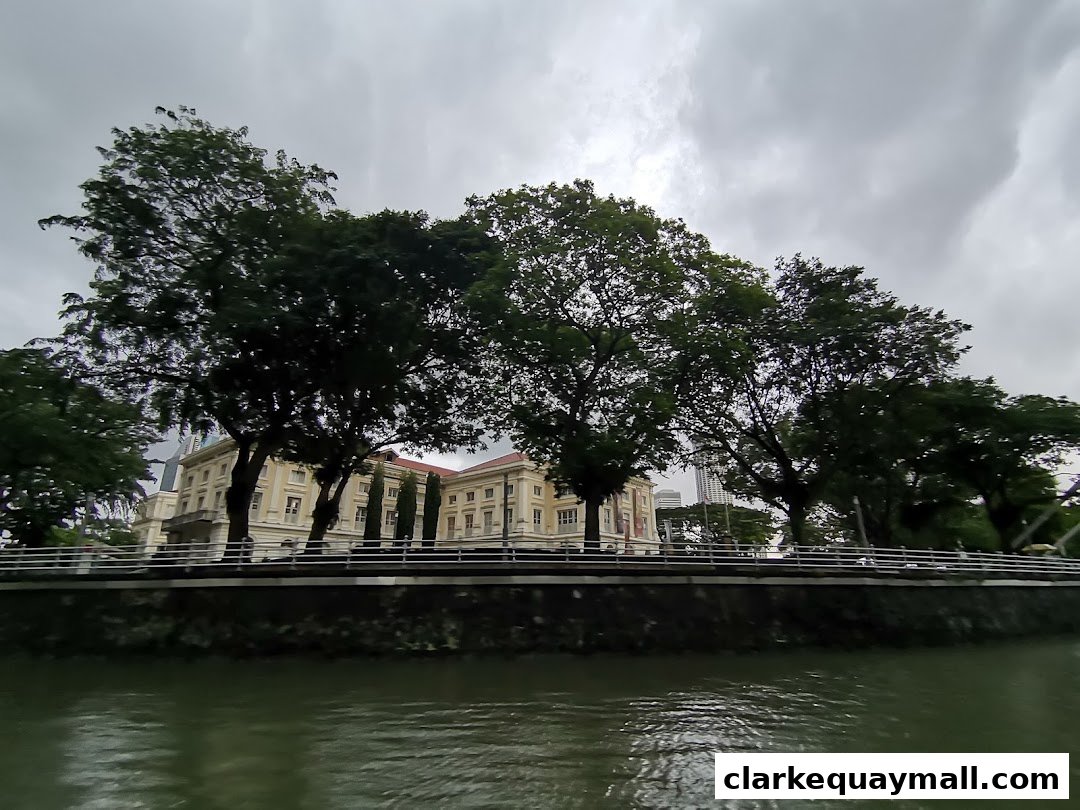 A scenic view of the Singapore River with lush trees and historic buildings.