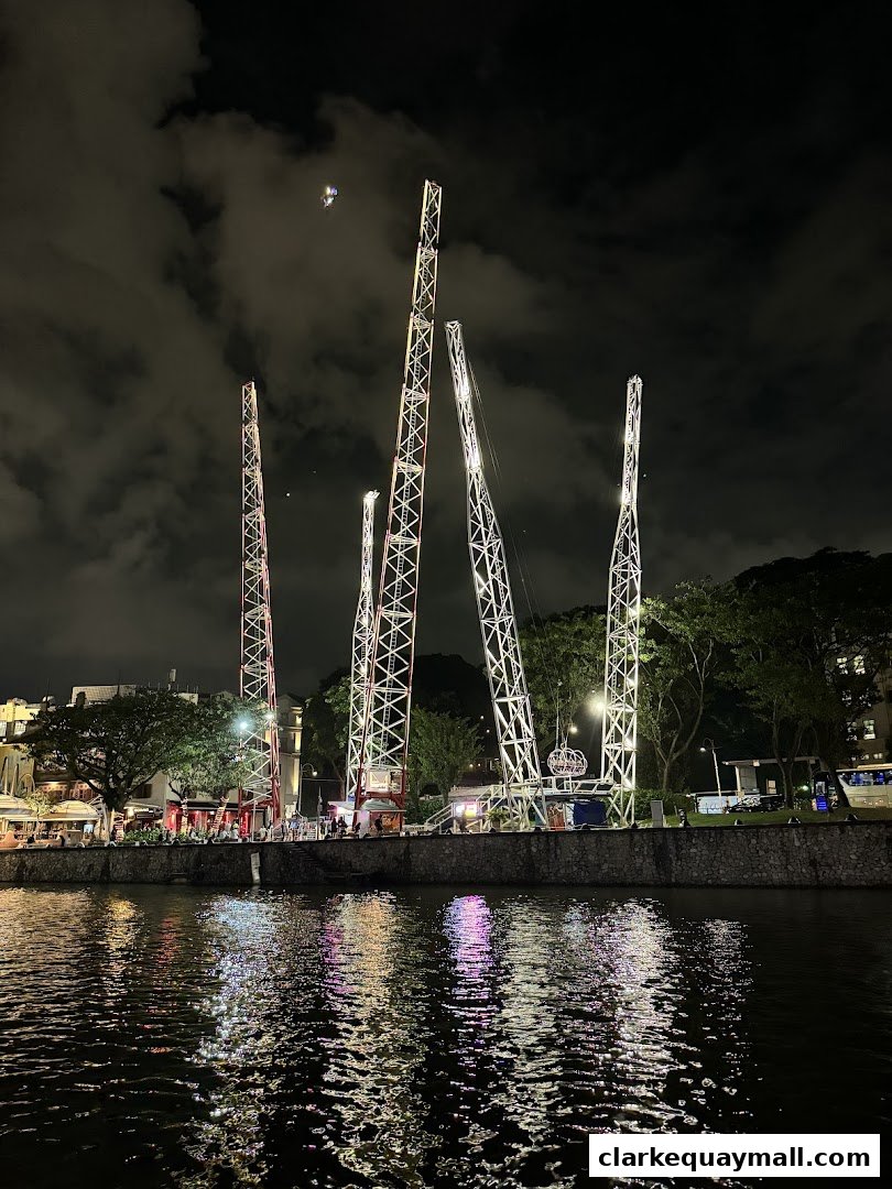 Night view of the Slingshot Singapore attraction with towering structures and reflections in the water.
