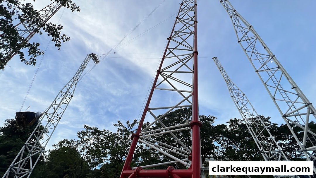 Tall metal towers with cables against a cloudy sky, with trees and buildings in the background.